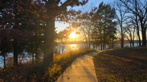 pathway surrounded by greenery with view of lake and sun shining at Table Rock Lakeshore Trail in Branson, Missouri, USA